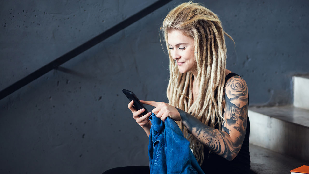 Tattooed and pierced young woman checking her smartphone