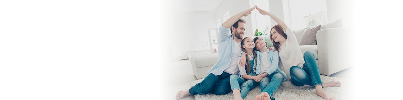 Familie sitzt auf Teppich vor dem Sofa