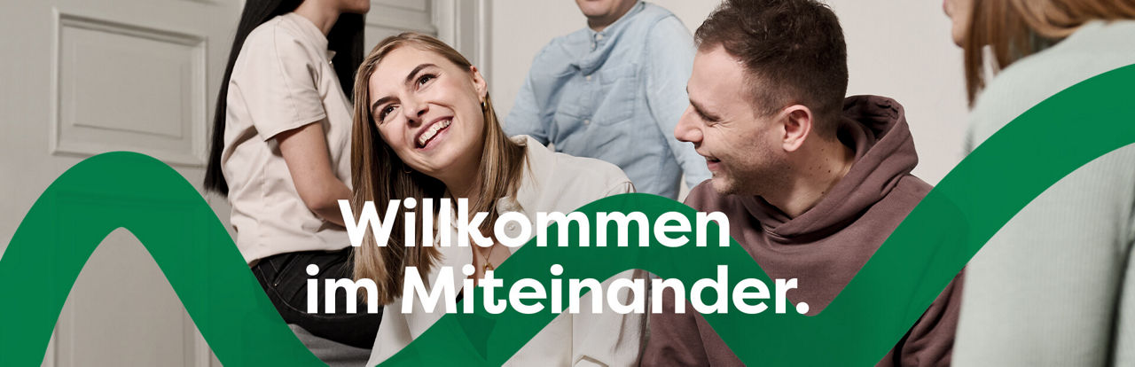 Eine junge Frau und ein junger Mann sitzen lächelnd nebeneinander
