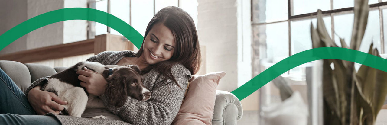 Eine Frau sitzt mit ihrem Hund auf der Couch