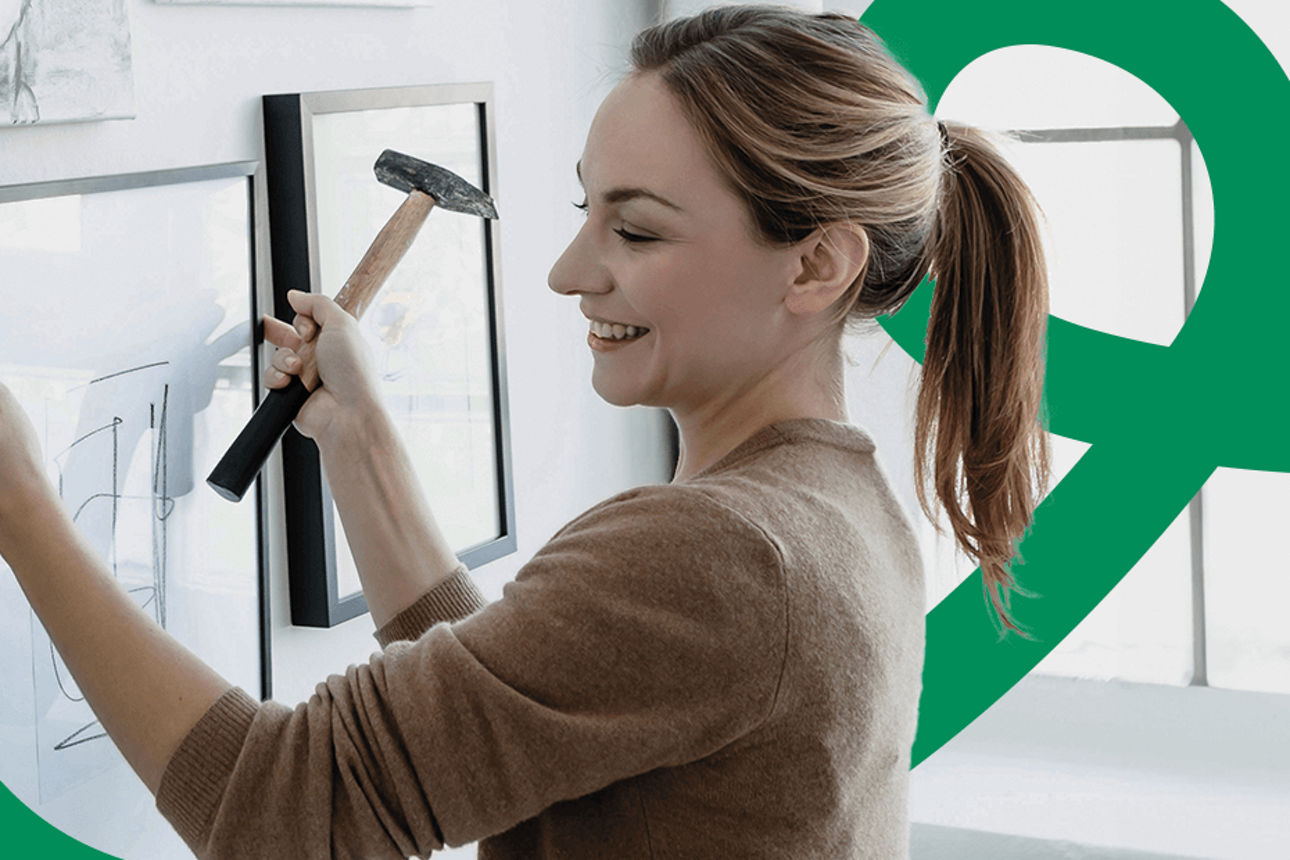 Eine Frau hängt ein Bild auf