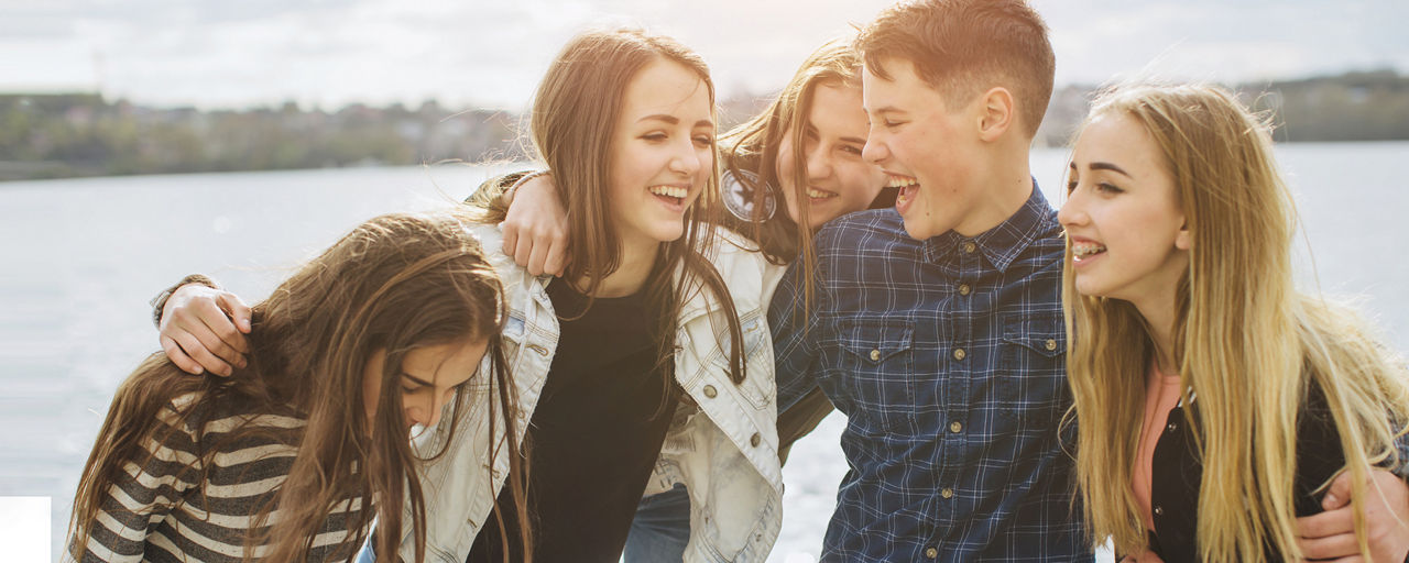 Fünf Jugendliche lachen zusammen am See