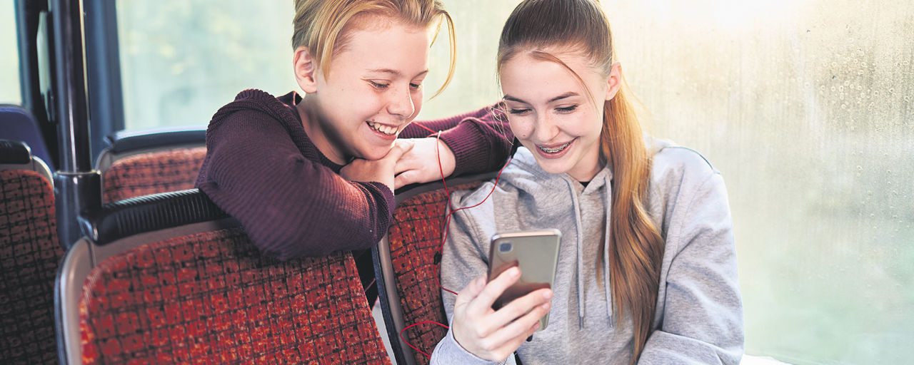 Zwei Jugendliche mit Handy im Bus