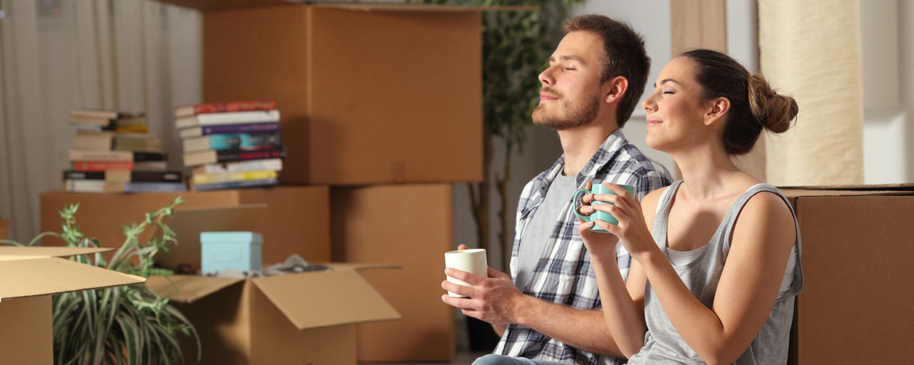 Frau und Mann mit Tasse zwischen Umzugskartons