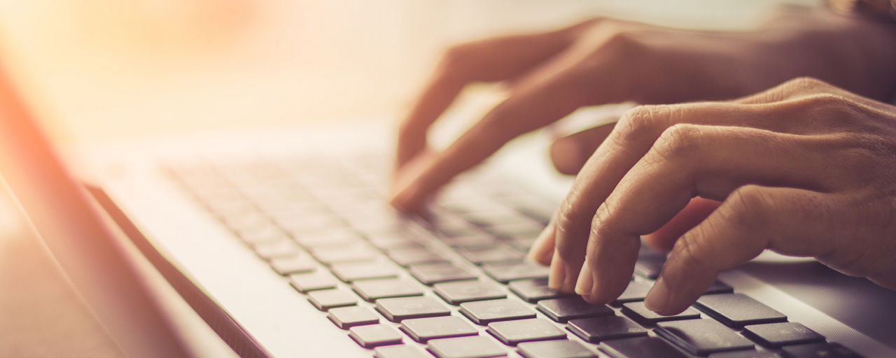 Eine Person hat die Hände auf der Tastatur und schreibt