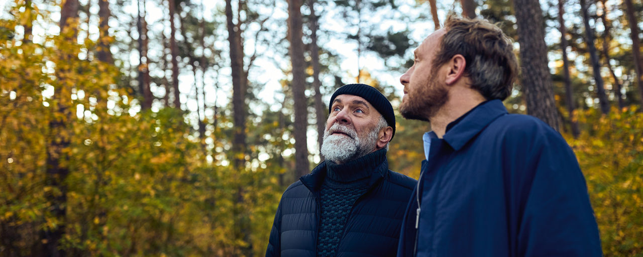 Zwei Männer stehen im Wald und sehen in den Himmel