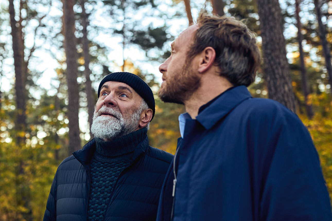 Zwei Männer stehen im Wald und sehen in den Himmel