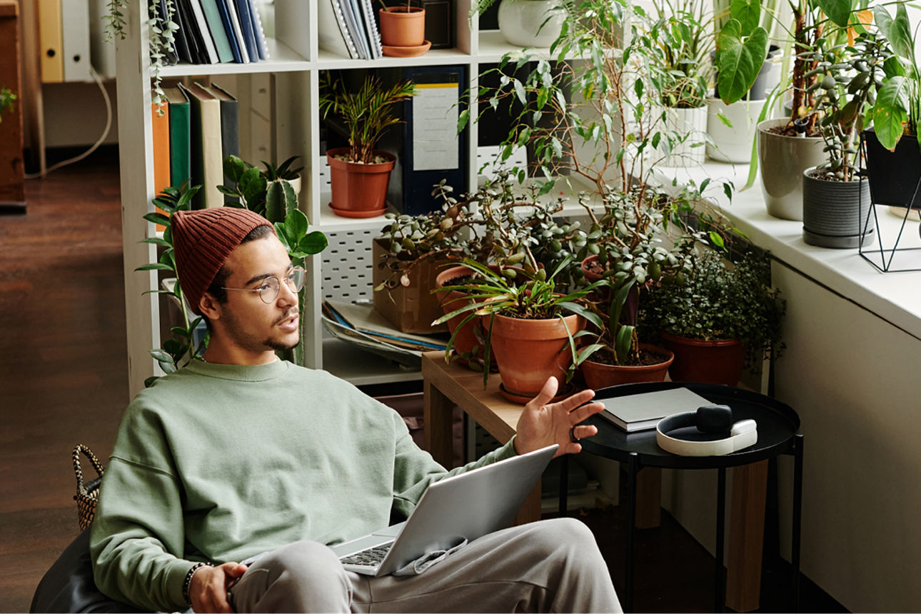 Mann im Sitzsack mit Laptop und Frau mit Tablet auf Fensterbank sitzend
