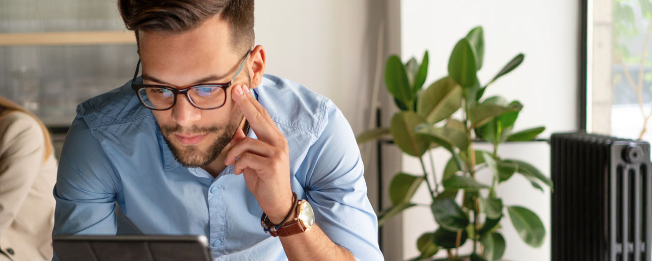 Mann mit Brille schaut auf ein Tablet