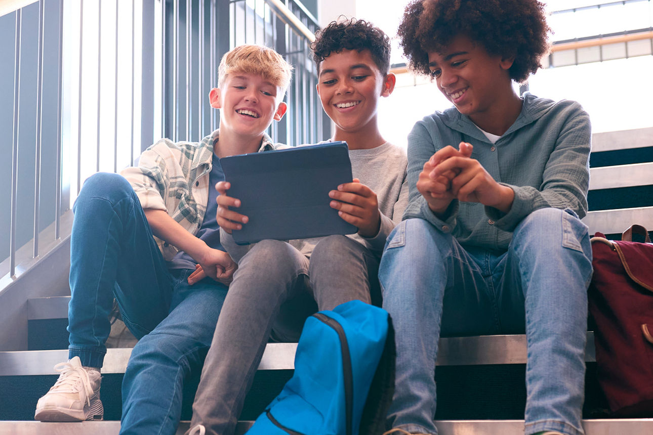 Schülerinnen und Schüler sitzen lächelnd in einem Klassenraum