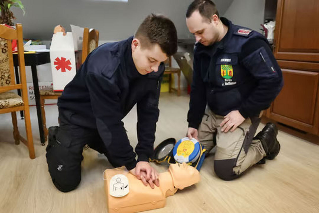 zwei Einsatzkräfte über Wiederbelebungsmaßnahmen an einer Puppe