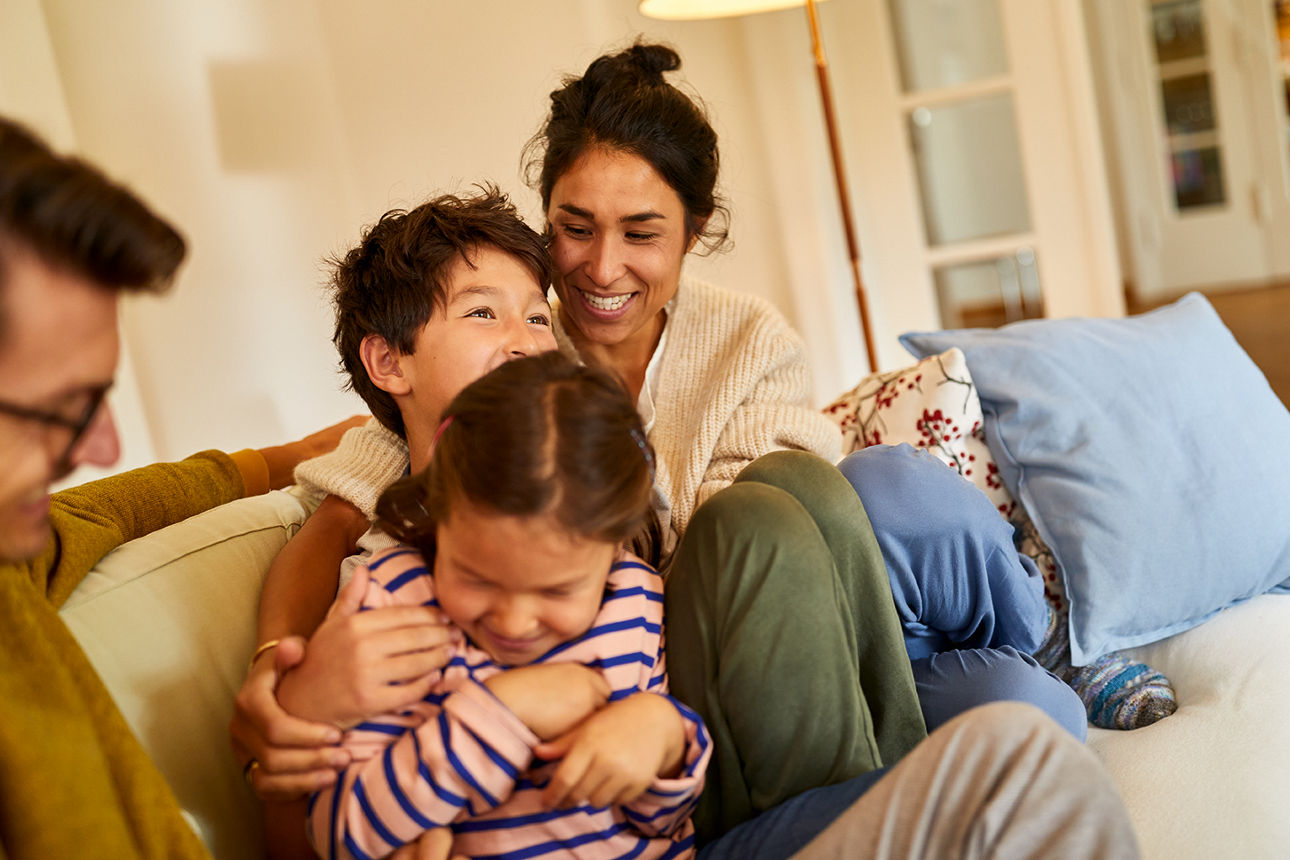 Personen sitzen zusammen auf einem Sofa in einem hellen Wohnzimmer