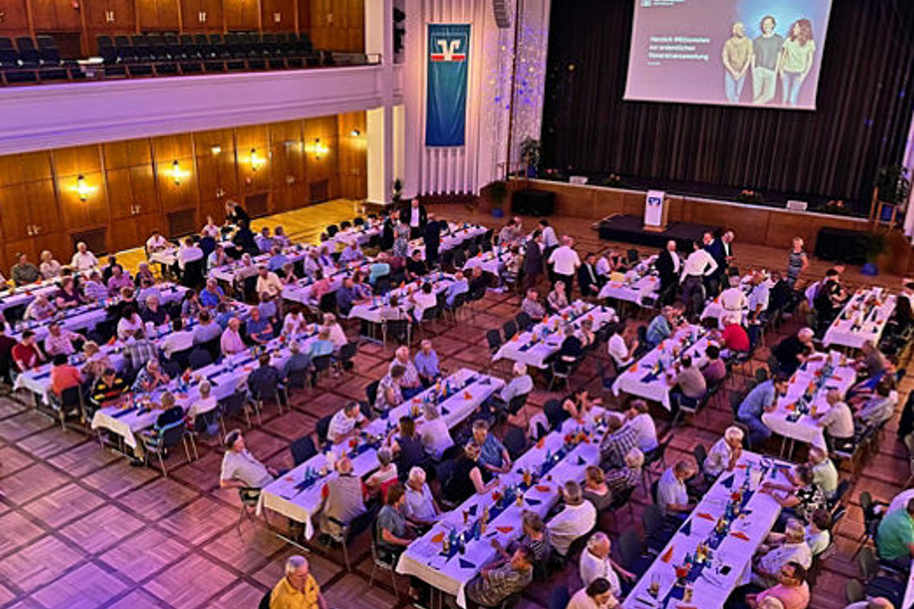 Die Mitglieder der Volks- und Raiffeisenbank Saale-Unstrut sitzen an Tischen bei der Mitgliederversammlung 2025