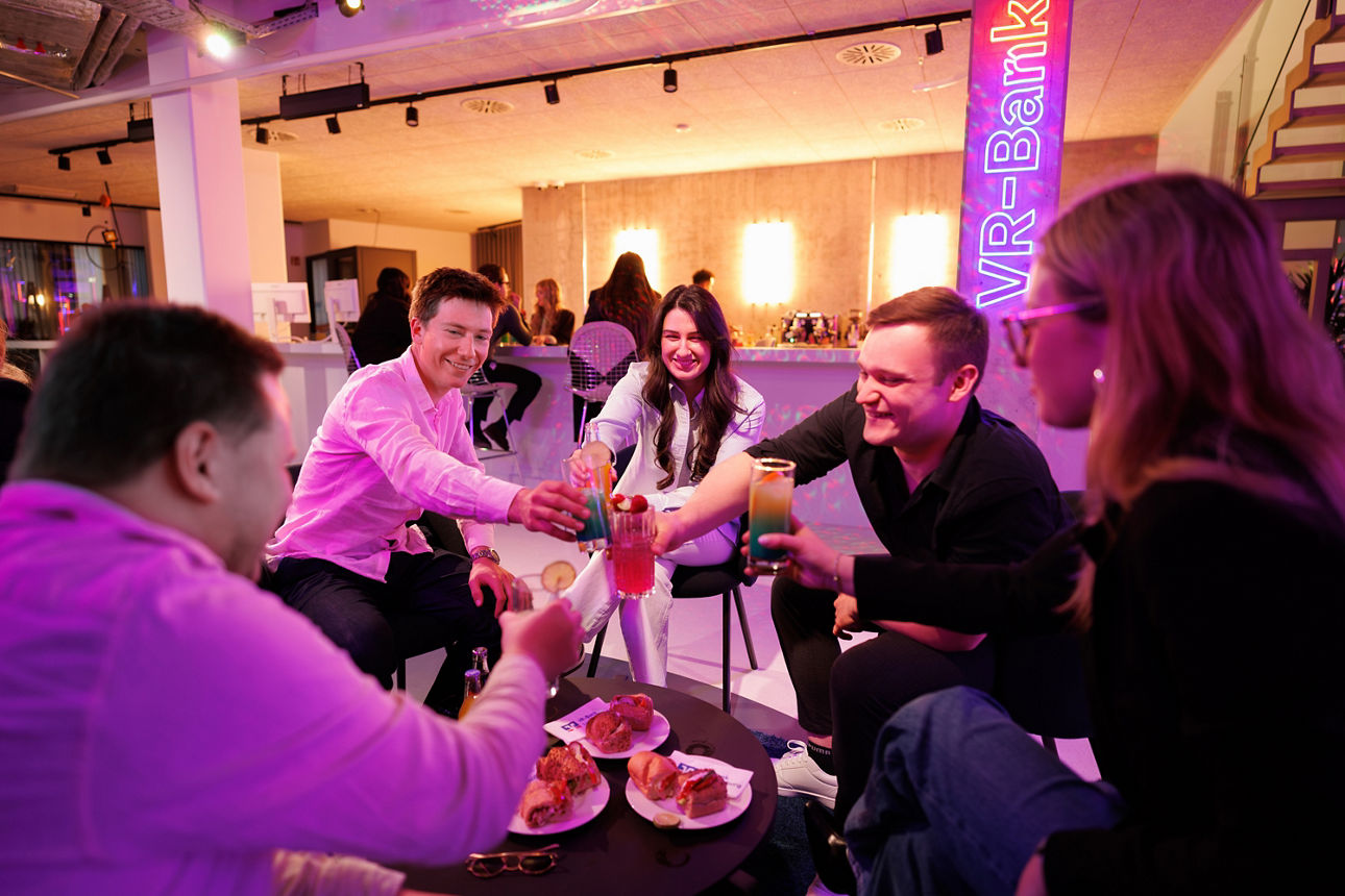 Gruppe Jugendlicher beim Anstoßen in der Lounge in der neuen VR-Bar