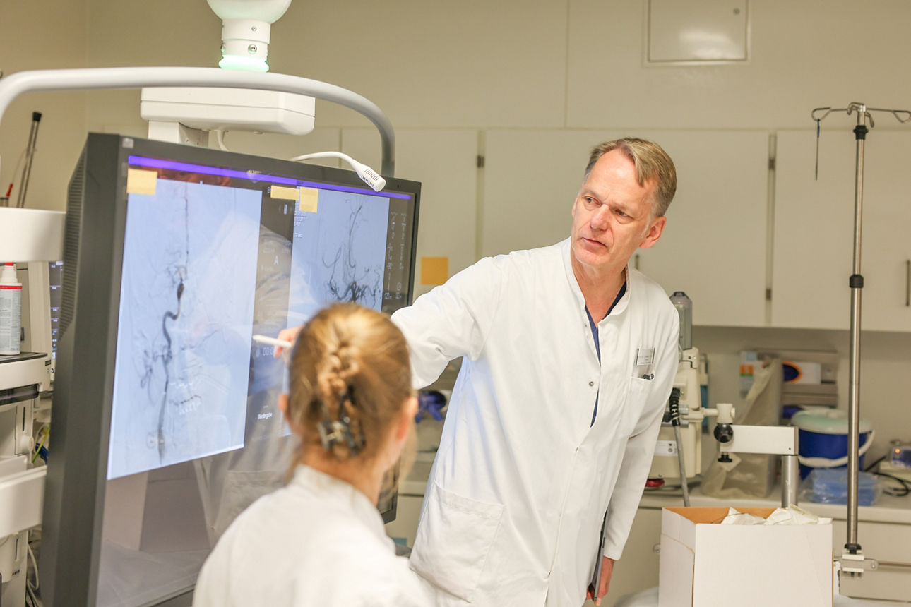 Zwei Personen in weißer Arbeitskleidung in einem medizinischen Umfeld