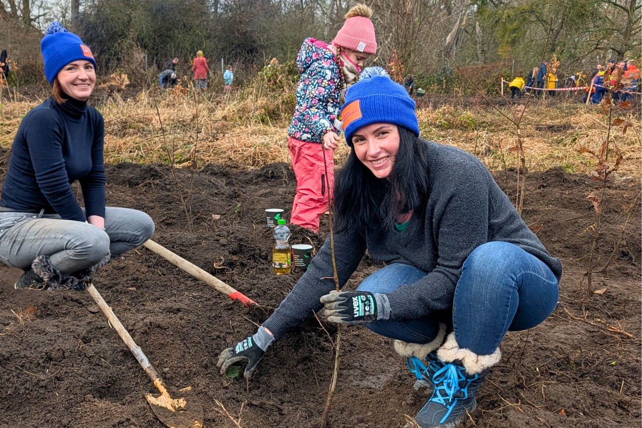 Zwei junge Frauen lächeln beim Einpflanzen eines Setzlings