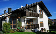  ein zweistöckiges Haus mit weißem Äußeren und einem dunkelbraunen Dach