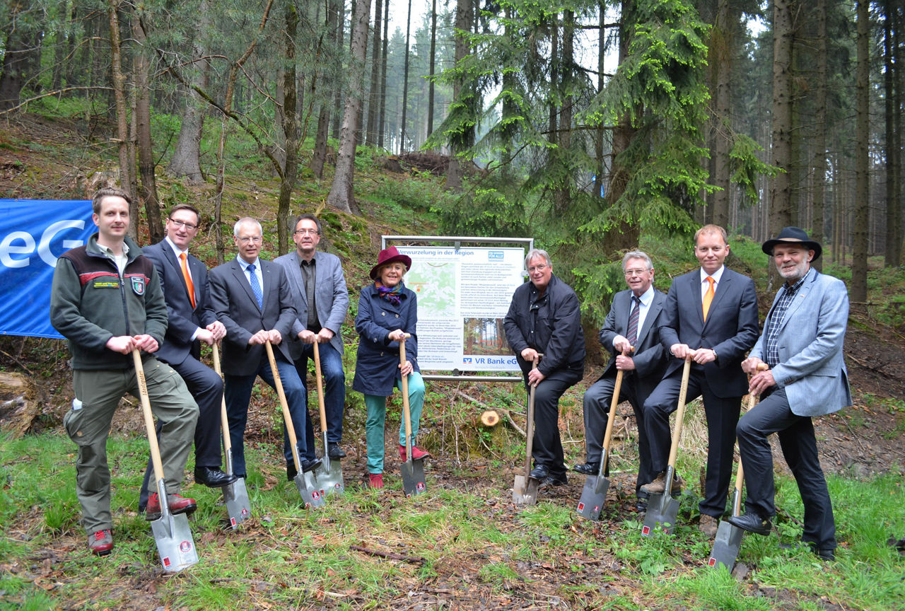 Mitgliederwald Rösrath - Foto: 9 Personen stehen mit einer Schaufel vor einer Infotafel im Wald
