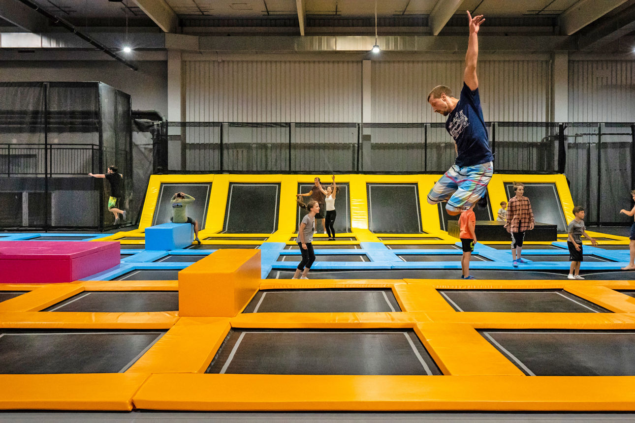 Kinder und Erwachsene springen auf einer Halle voller Trampoline