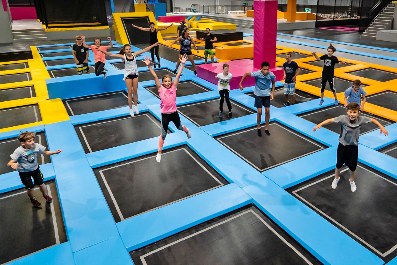 Kinder die in einer großen Halle auf mehreren Trampoline springen