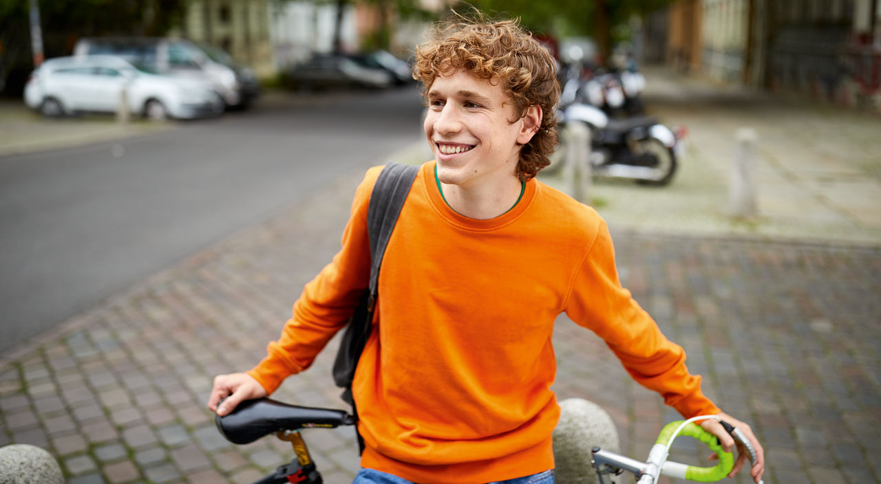 lächelnder Jugendlicher mit Fahrrad
