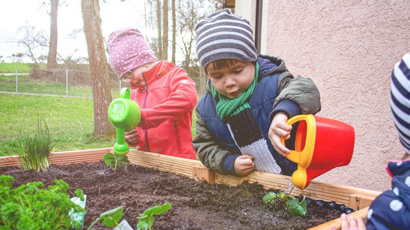 Kinder die ein Hochbeet bepflanzen