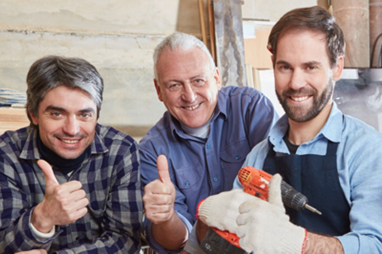 Erfolgreiche Handwerker als Team halten die Daumen hoch