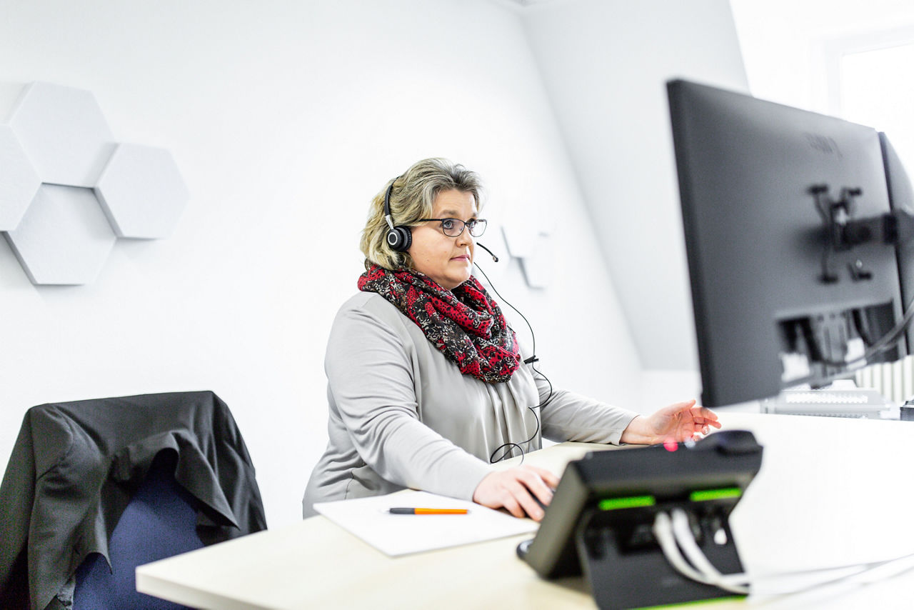 Eine Frau mit Headset an einem Schreibtisch