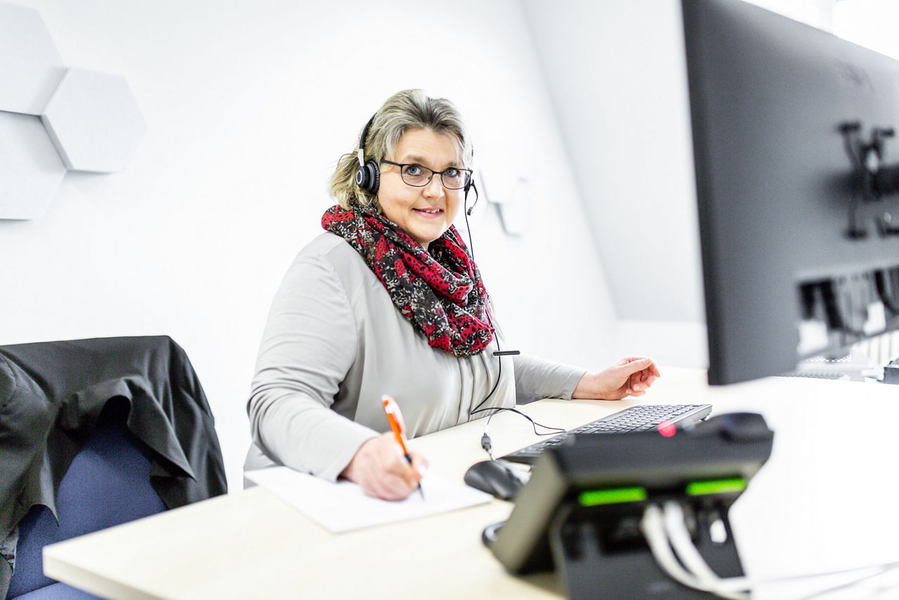 Bankmitarbeiterin mit Headset am Computer