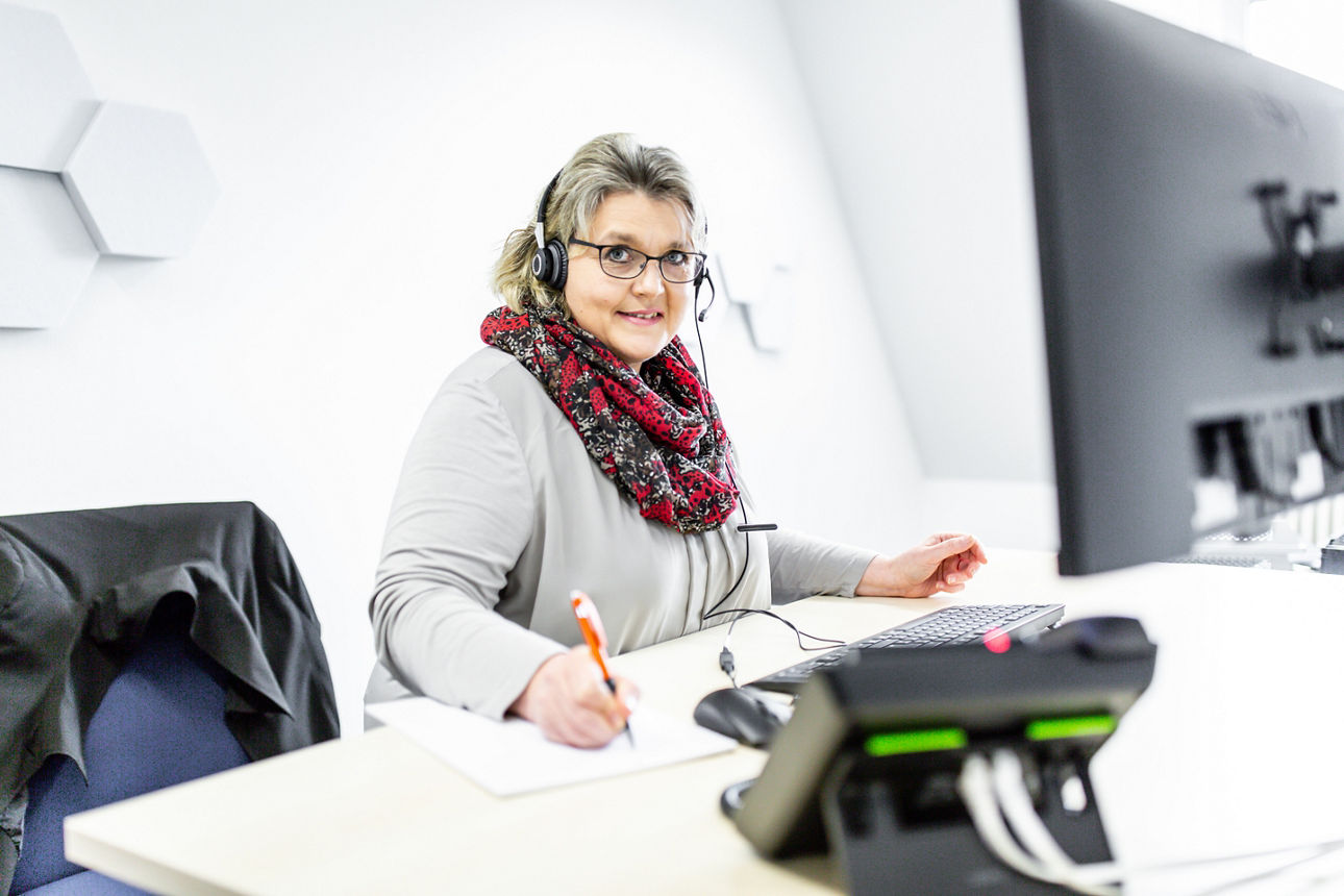 Bankmitarbeiterin mit Headset am Computer