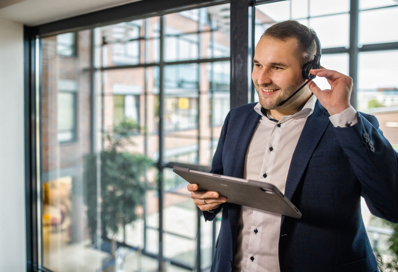 Mitarbeiter der VR DirektFiliale hat ein Headset auf und ein Tablet in der Hand