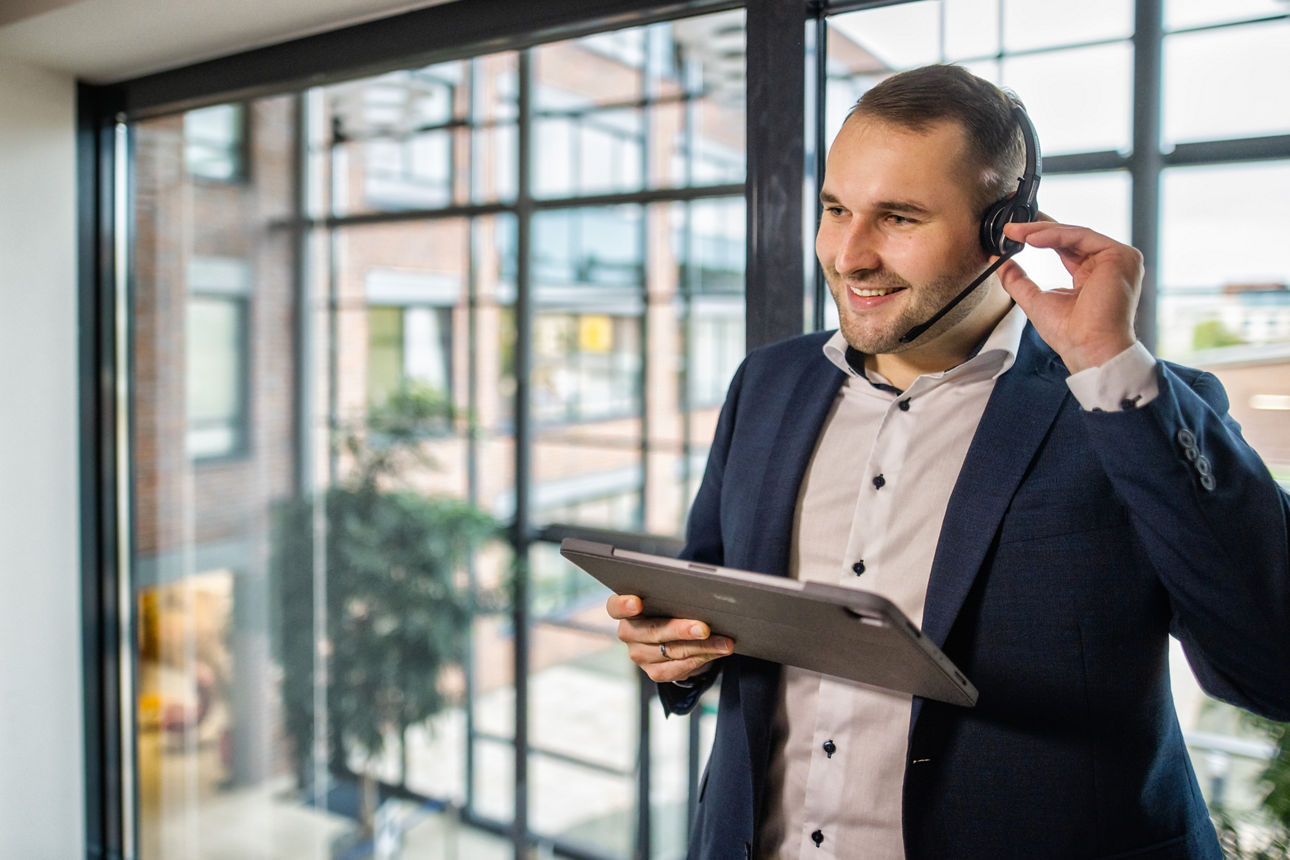 Mitarbeiter der VR DirektFiliale hat ein Headset auf und ein Tablet in der Hand