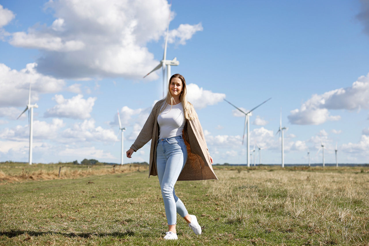 Eine Frau steht auf einer Weide vor einem Windpark