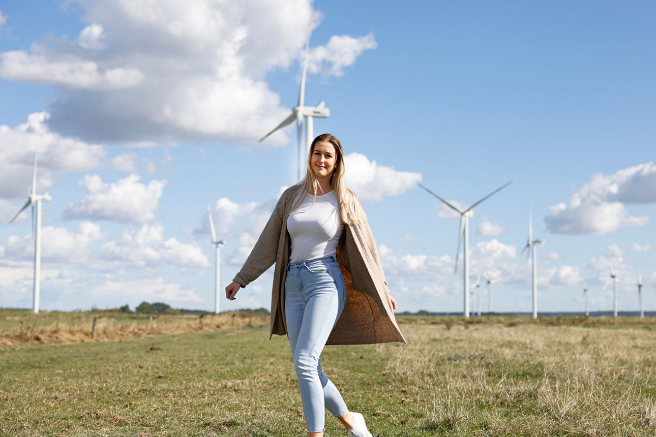 Eine Frau steht auf einer Weide vor einem Windpark