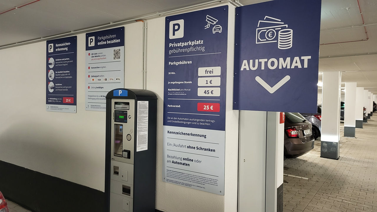 Kassenautomat in der Tiefgarage mit Tariftabellen und Bedienungshinweisen an der Wand.