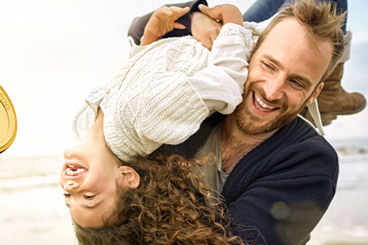 Mann mit Kind auf der Schulter am Strand und die Abbildung von Goldmünzen