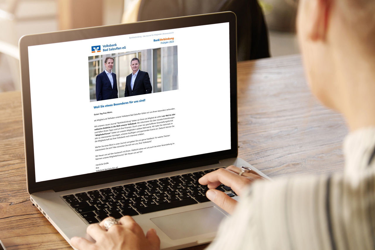 Frau am aufgeklappten Laptop, auf dem Laptop ist ein Artikel des Journals BankVerbindung zu sehen