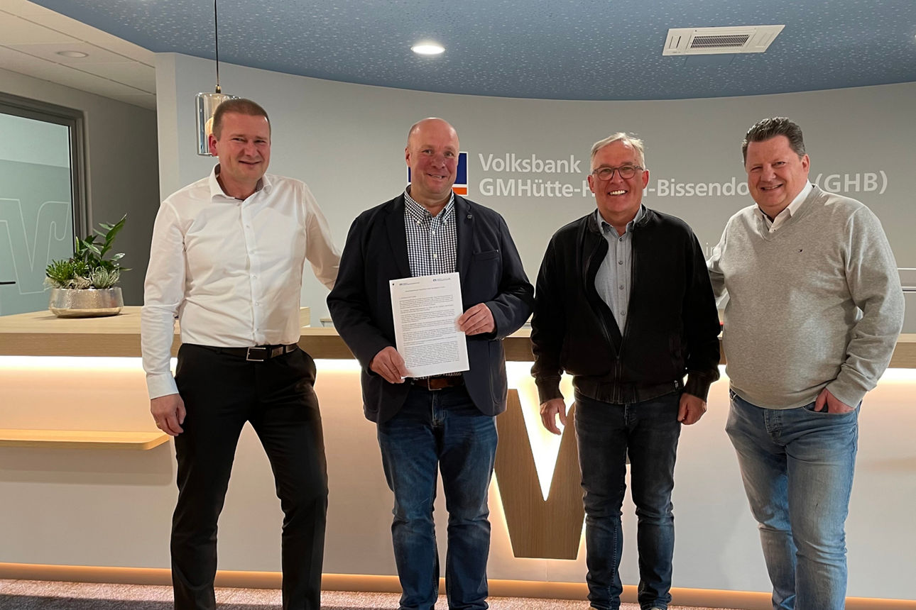 Vier elegant gekleidete Männer, die die Fusion von zwei Banken unterzeichnet haben