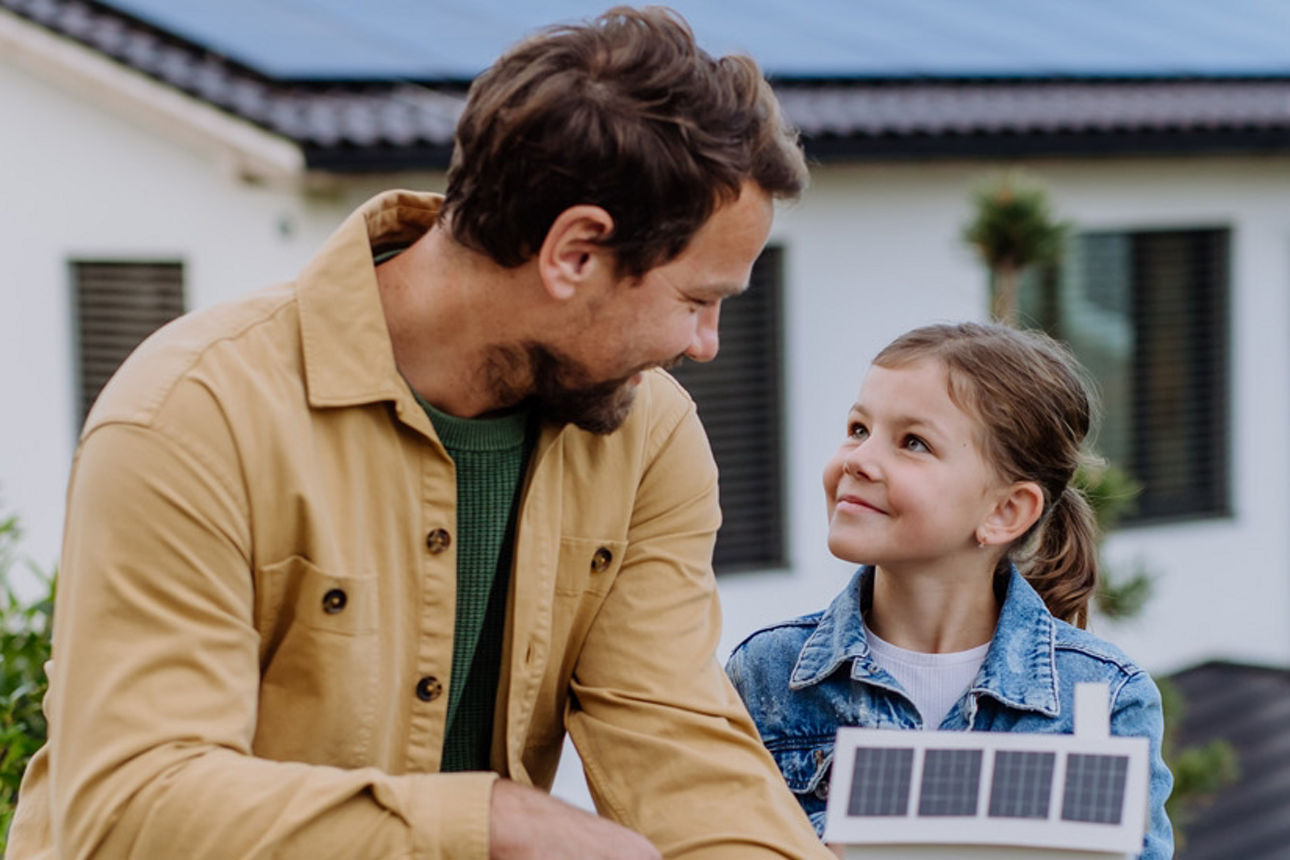 Papa mit Kind vor einem Haus