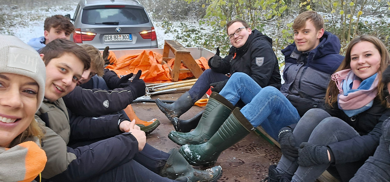 Eine Gruppe von Freunden sitzt auf einer Holzplattform in einem verschneiten Wald