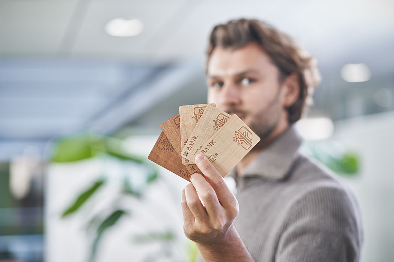 Ein Mann präsentiert vier Holzkarten in seiner Hand 