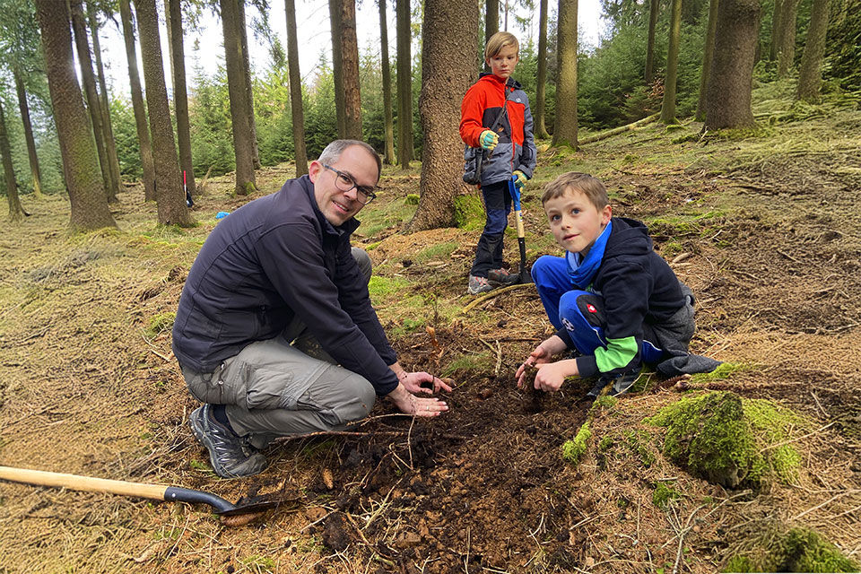 Vater und seine beiden Söhne beim pflanzen eines Baums