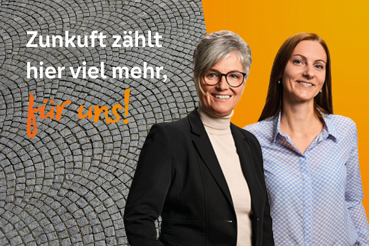 Zwei lächelnde Kolleginnen stehen nebeneinander