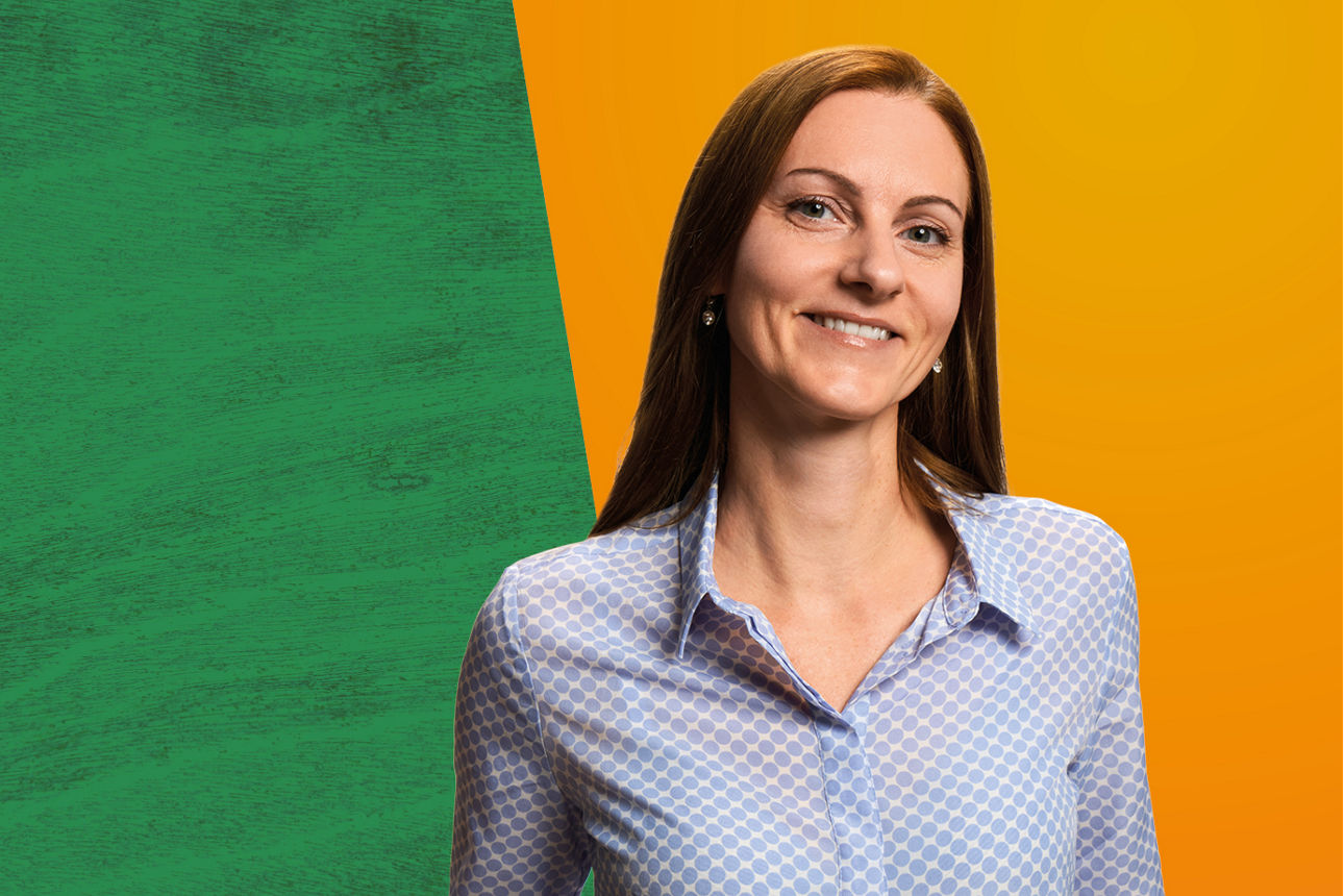 Kollegin steht vor grün/orangenem Hintergrund