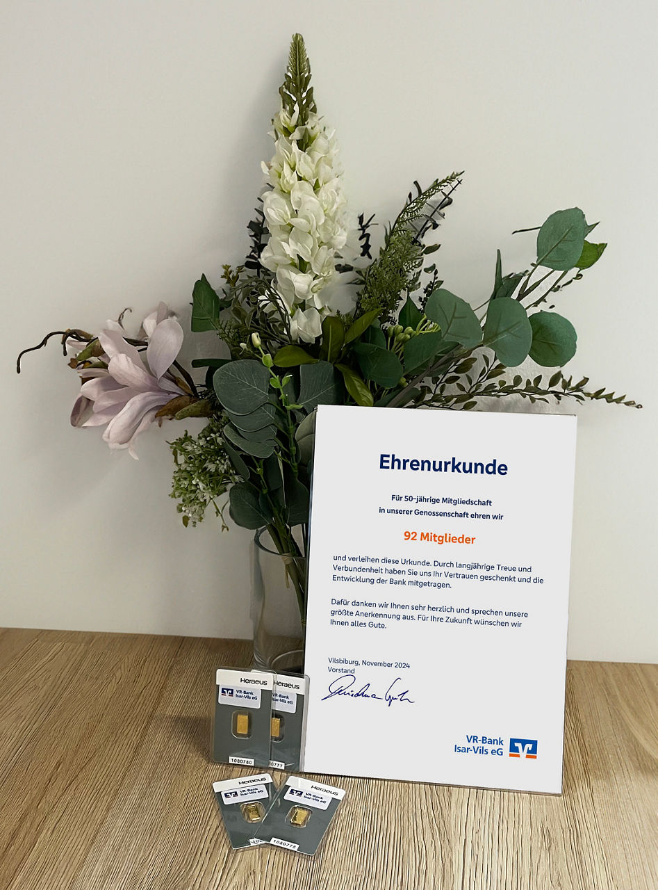 Blumenstrauß mit Ehrenurkunde und Goldbarren.