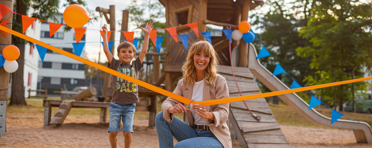 Junge Frau schneidet oranges Band durch bei Spielplatzeröffnung