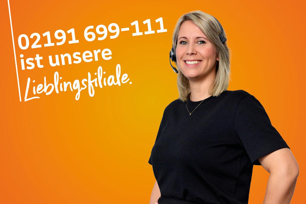 Kollegin im schwarzen T-Shirt steht vor orangenem Hintergrund mit Lieblingsfilialschriftzug