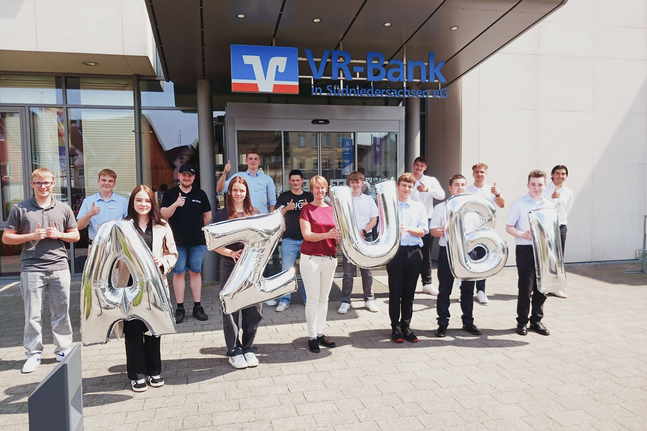 Gruppenfoto mit allen neuen Azubis. Es werden Ballons mit hochgehalten, die das Wort Azubi ergeben