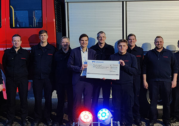 Die Feuerwehrleute und ein Mitarbeiter der Bank stehen zusammen, die Feuerwehr bekommt einen Scheck überreicht.