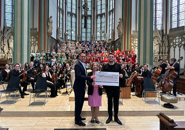 Markus Albermann übergibt symbolisch den 3.000 Euro-Scheck an den Universitätschor
